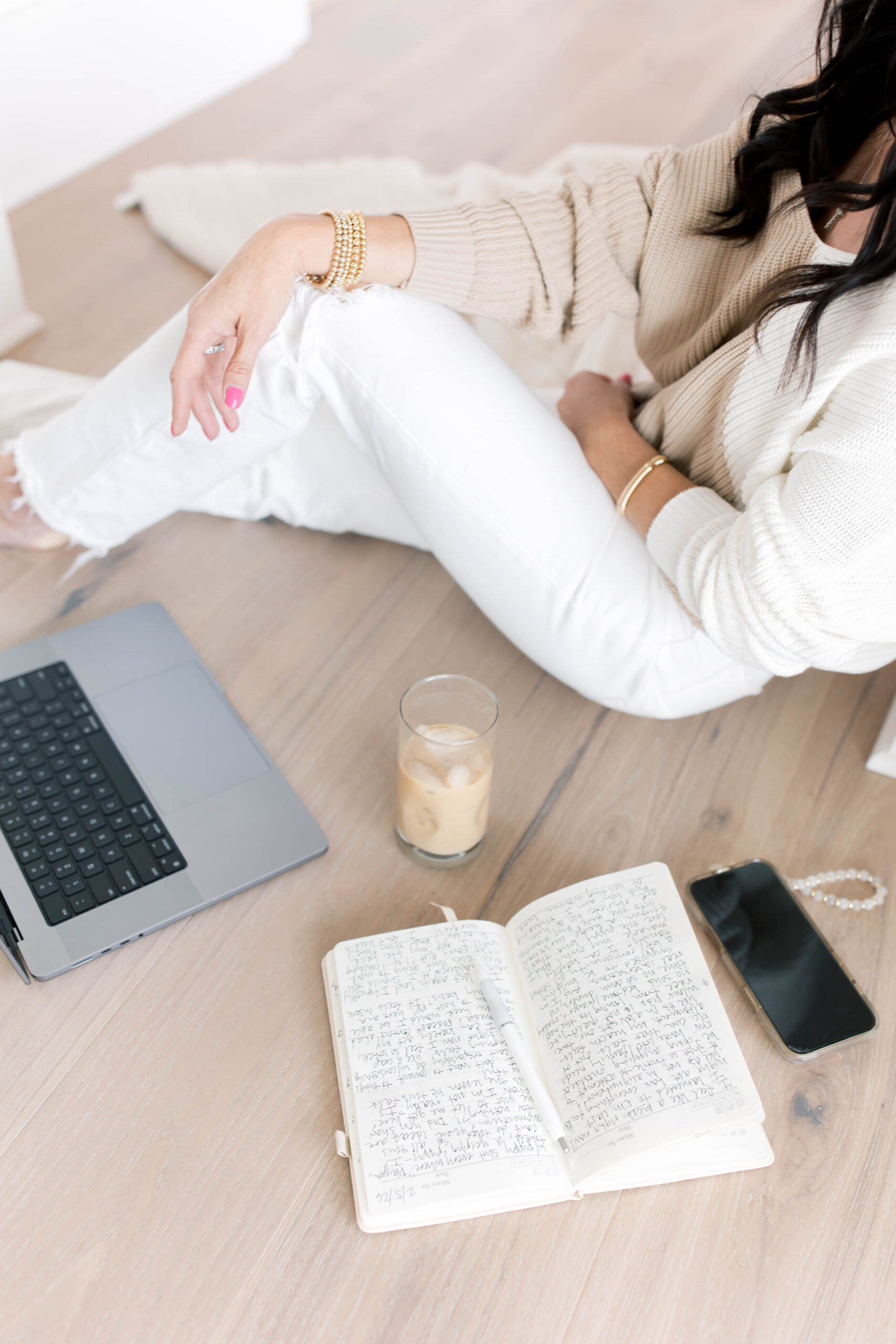 Woman sitting on the floor with her journal, iced coffee, and laptop, reflecting on her identity beyond motherhood